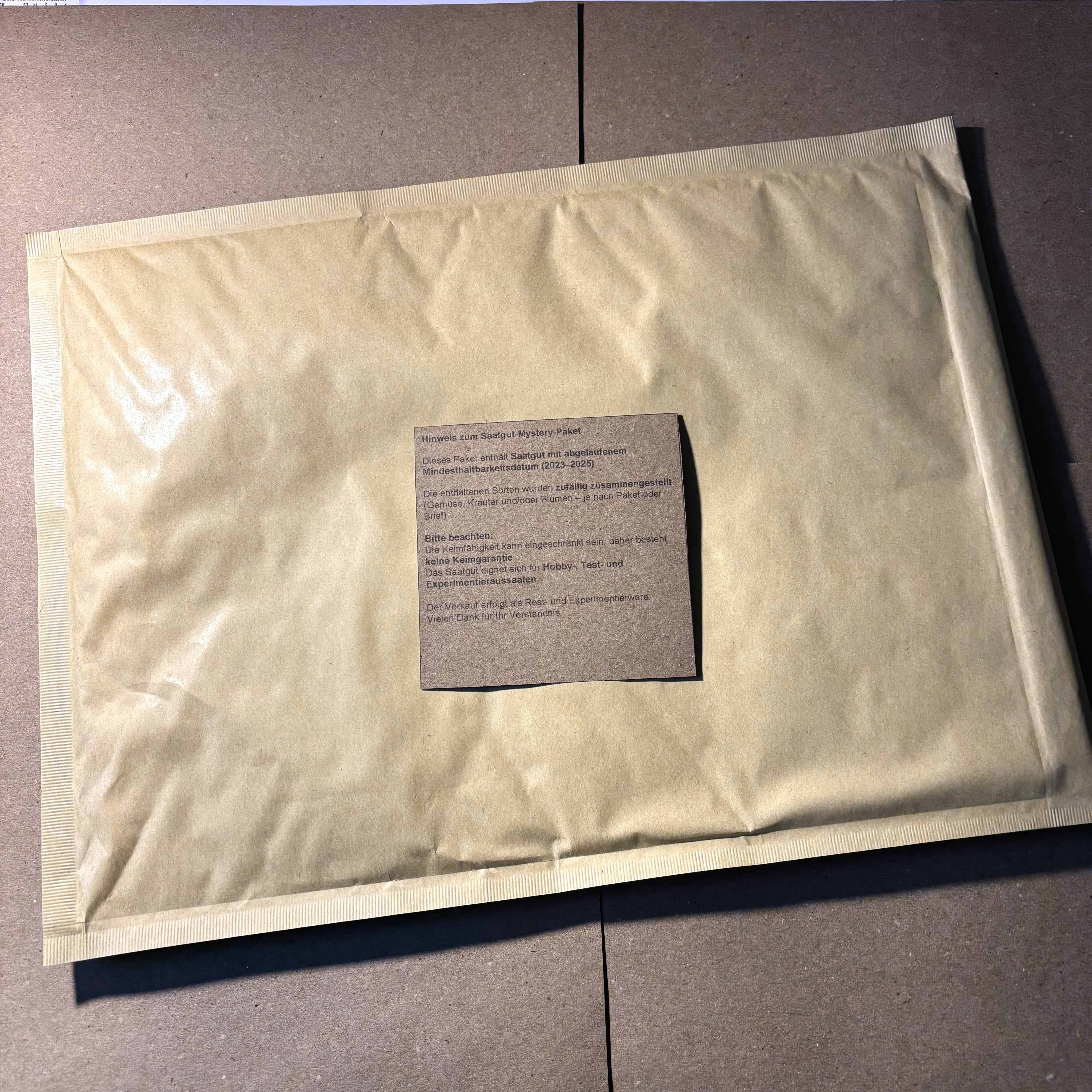 Versandfertiges Saatgut-Mystery-Paket im Briefumschlag mit Hinweiszettel zum Mindesthaltbarkeitsdatum