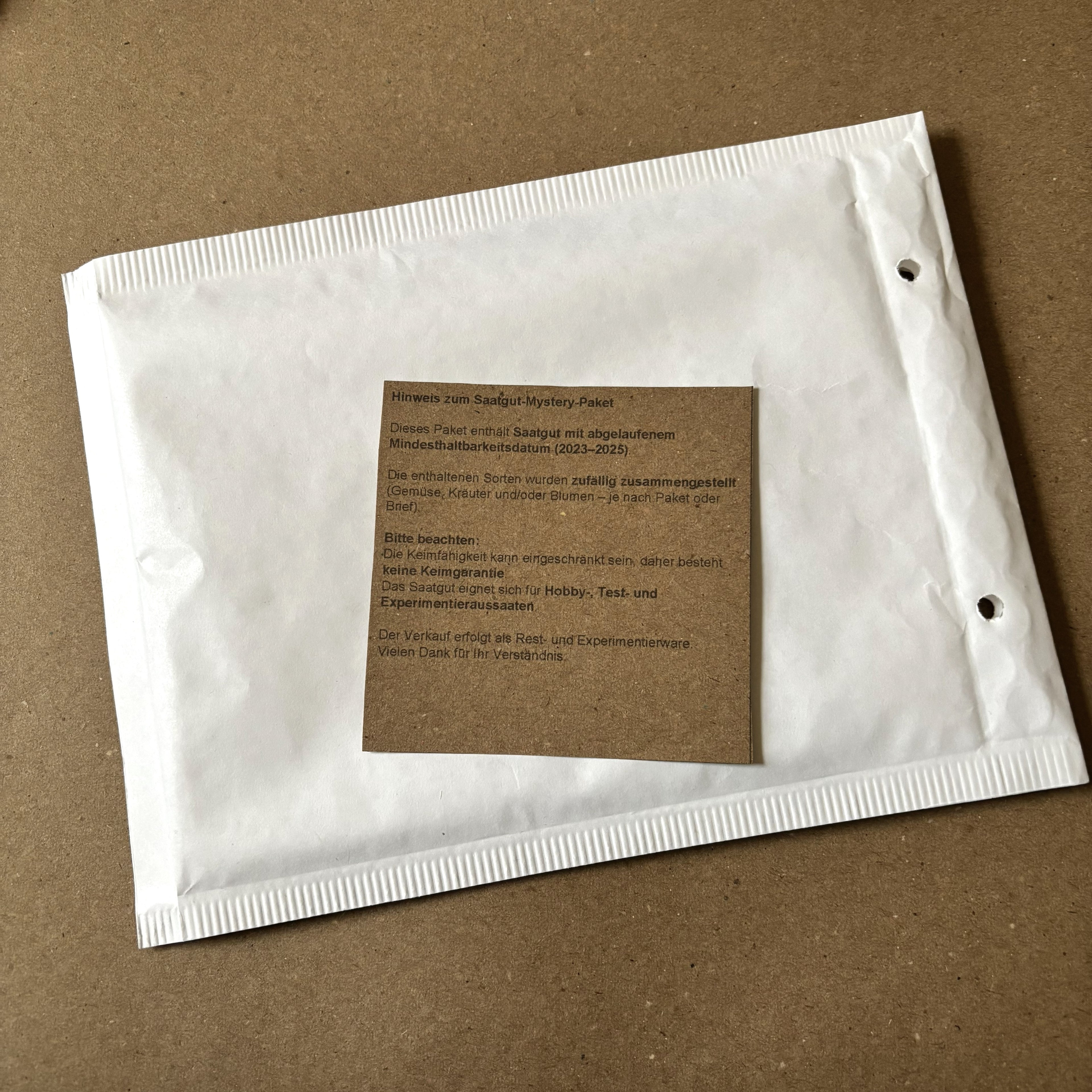 Versandfertiges Saatgut-Mystery-Paket im Briefumschlag mit Hinweiszettel zum Mindesthaltbarkeitsdatum